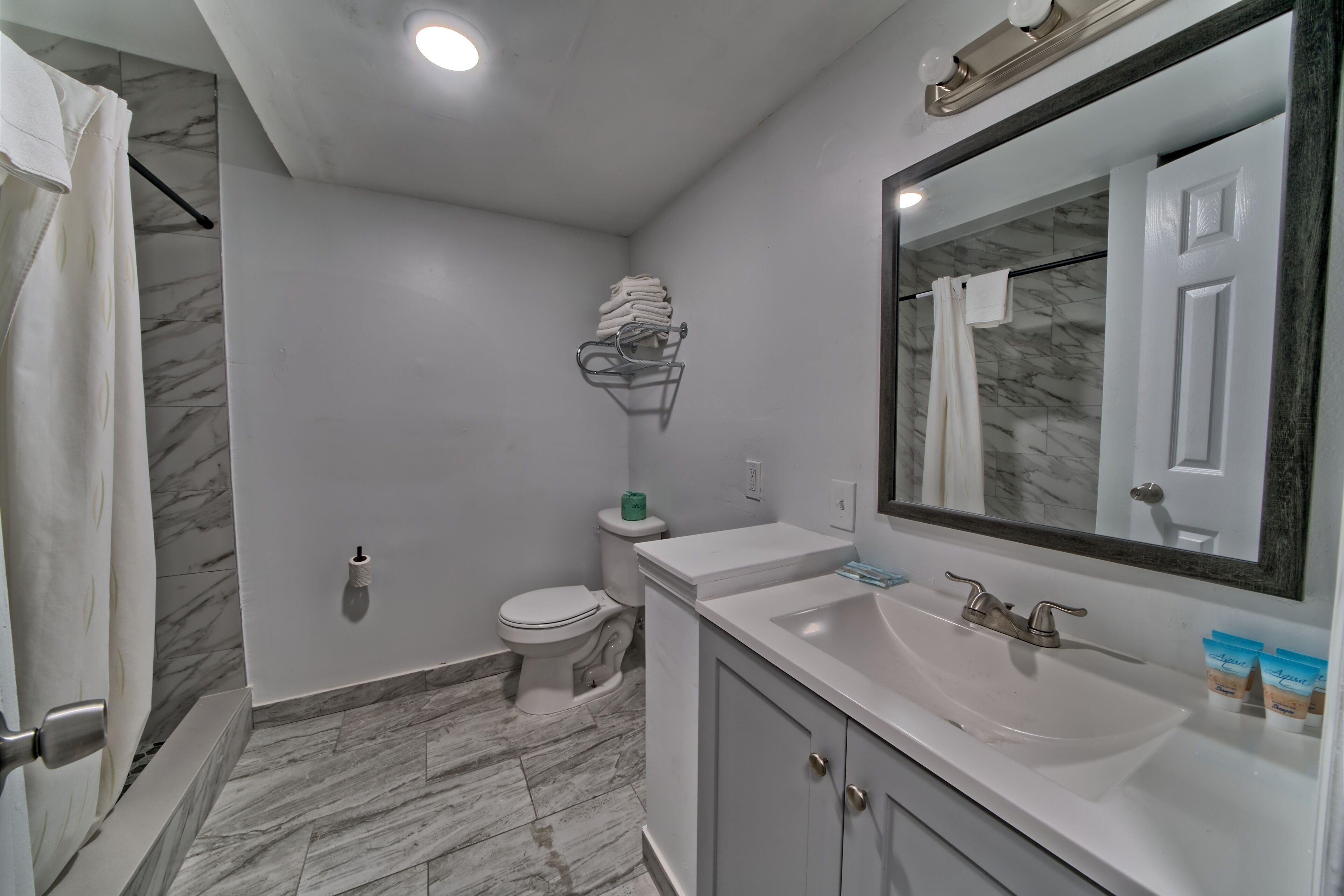 A bathroom with a toilet, sink, and mirror.