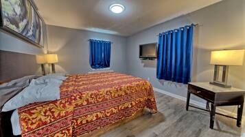 Une chambre d’hôtel avec un grand lit, un bureau, une télévision et deux lampes.