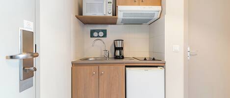 A compact kitchenette with a microwave, coffee maker, and a dishwasher.