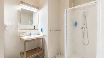 A bathroom with a sink, mirror, and shower.