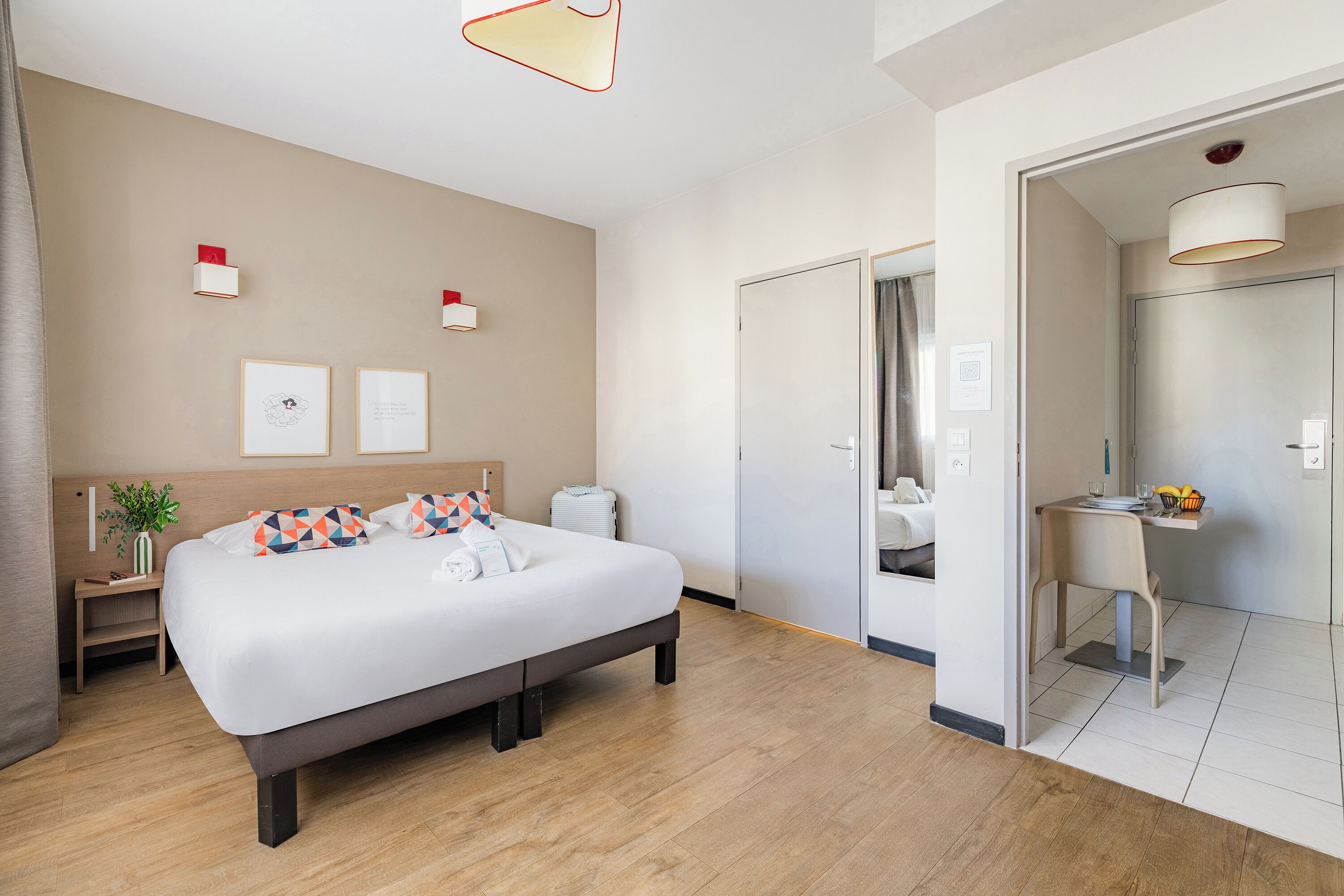 Una habitación de hotel moderna con una cama grande, mesitas de noche, un escritorio y un baño visible a través de una puerta abierta.