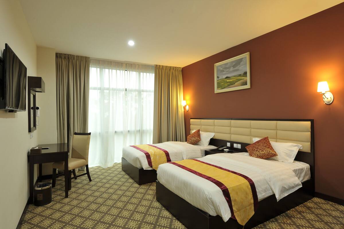 A hotel room with two beds, a desk, a chair, a television, and a painting on the wall.