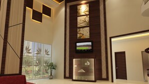 A modern lobby with a red sofa, a TV mounted on a wooden panel, and a glass display case. - Hallmark Regency Hotel - Johor Bahru (Johor Bahru)