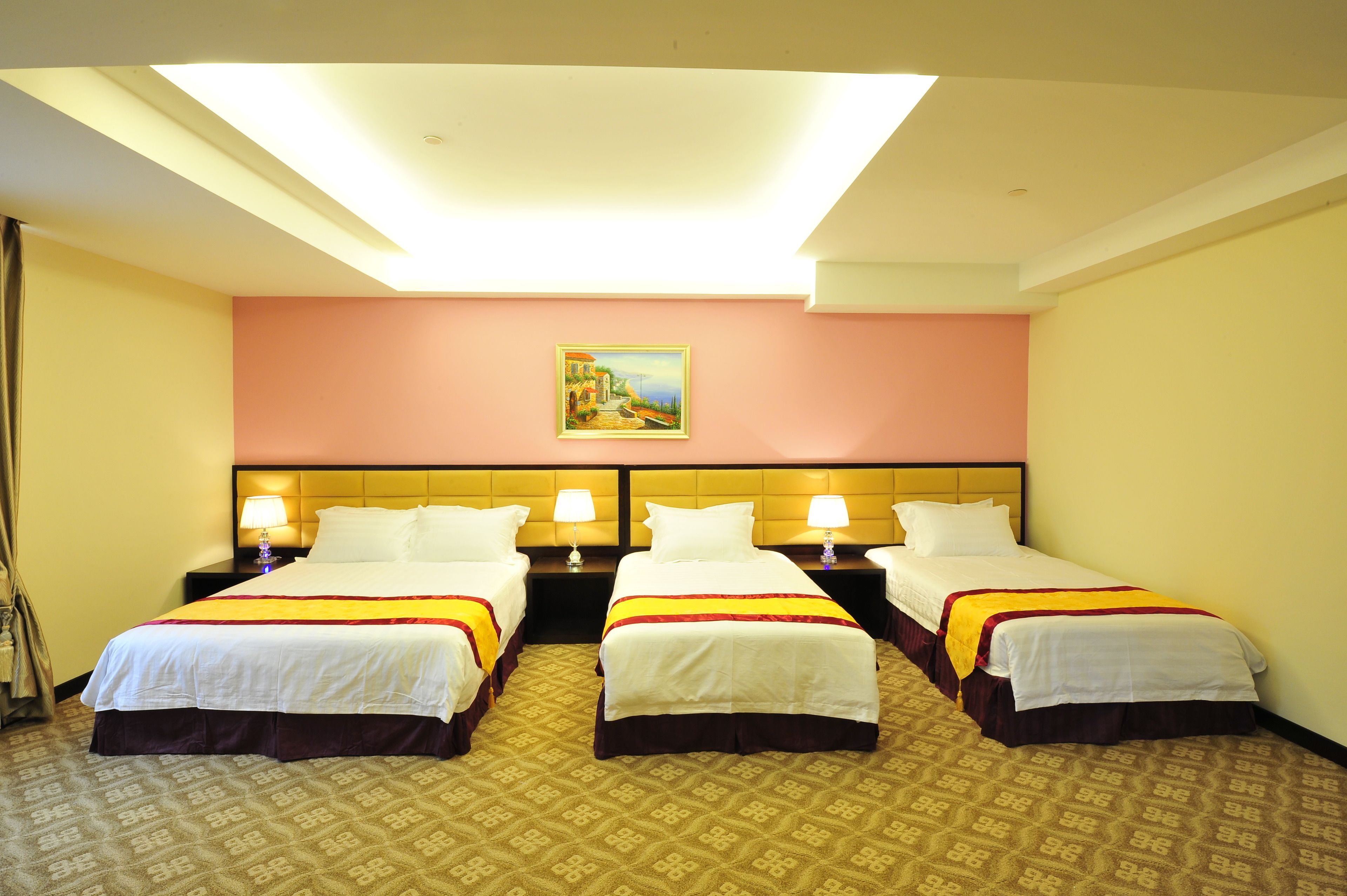 Una habitación de hotel con tres camas, un cuadro en la pared y una alfombra estampada.