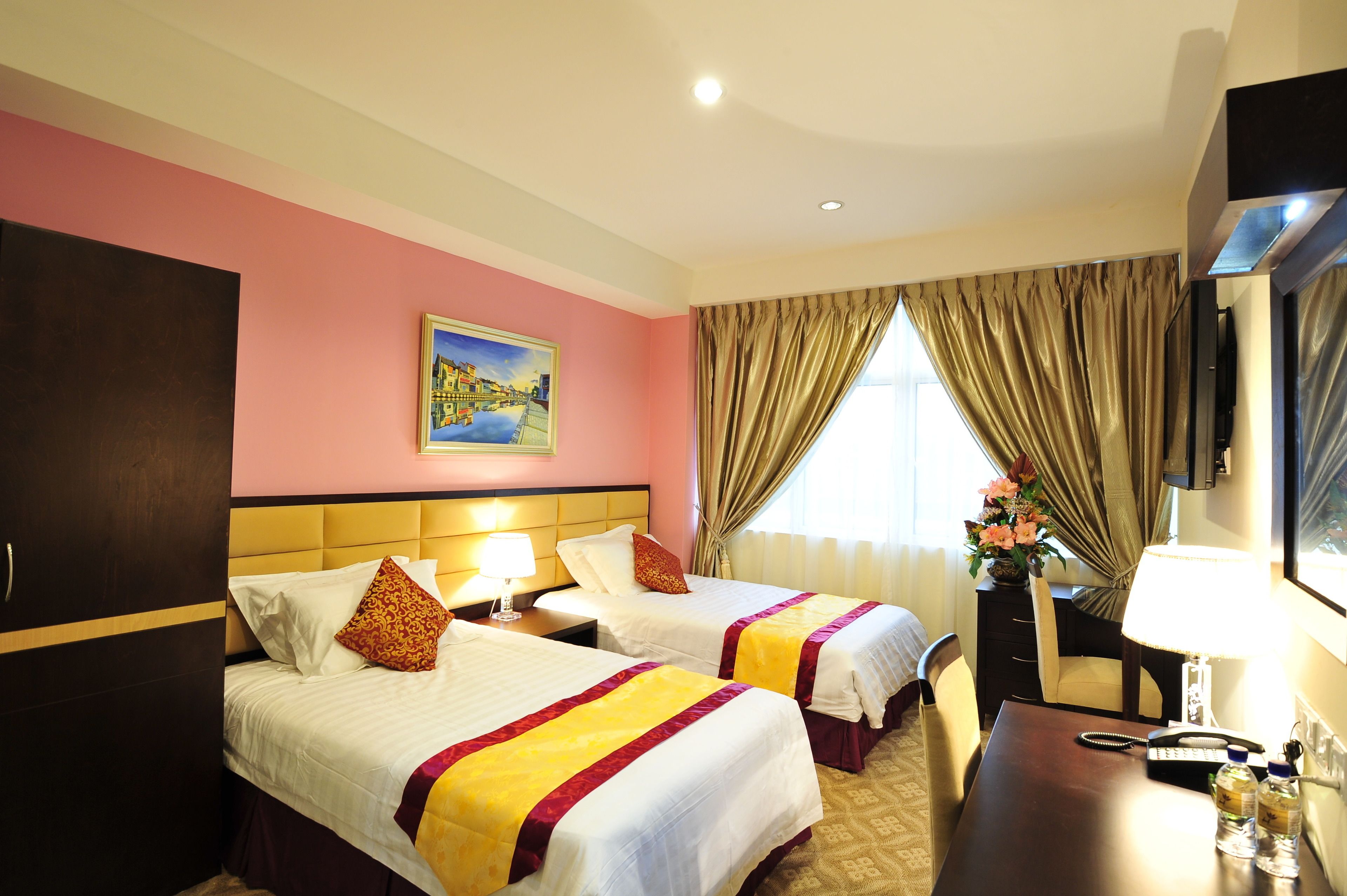A hotel room with two beds, a painting on the wall, a desk with a lamp, and a window with curtains.