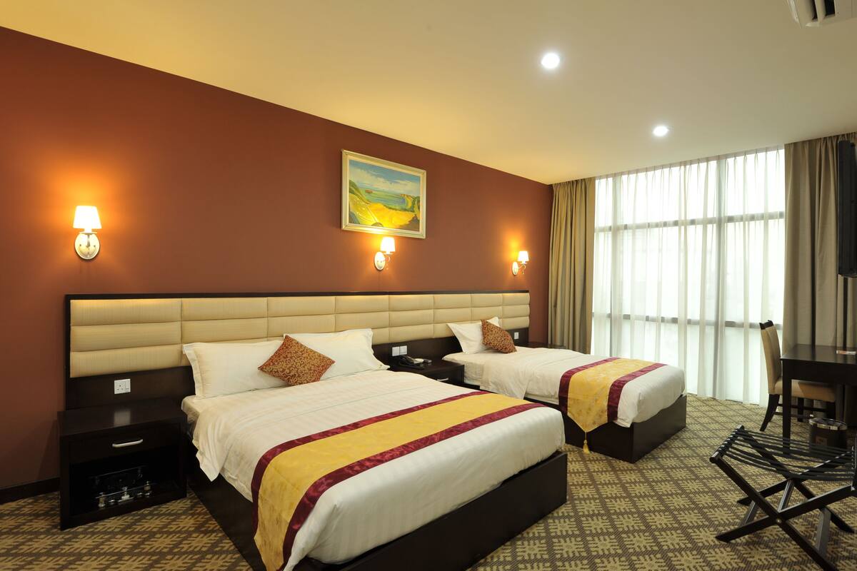 A hotel room with two beds, a desk, and a chair.