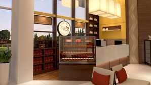 A modern coffee lounge with a bakery display, shelves with packaged goods, and a seating area with a view. - Hallmark Regency Hotel - Johor Bahru (Johor Bahru)