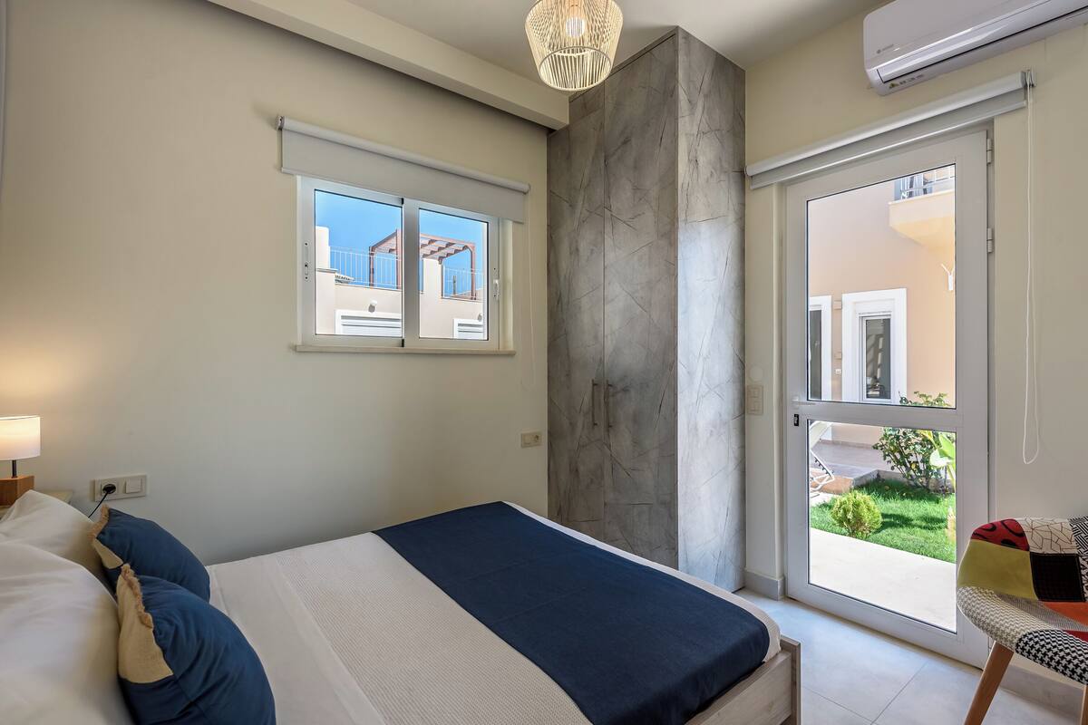 A bedroom with a bed, a window, a door, and a chair.