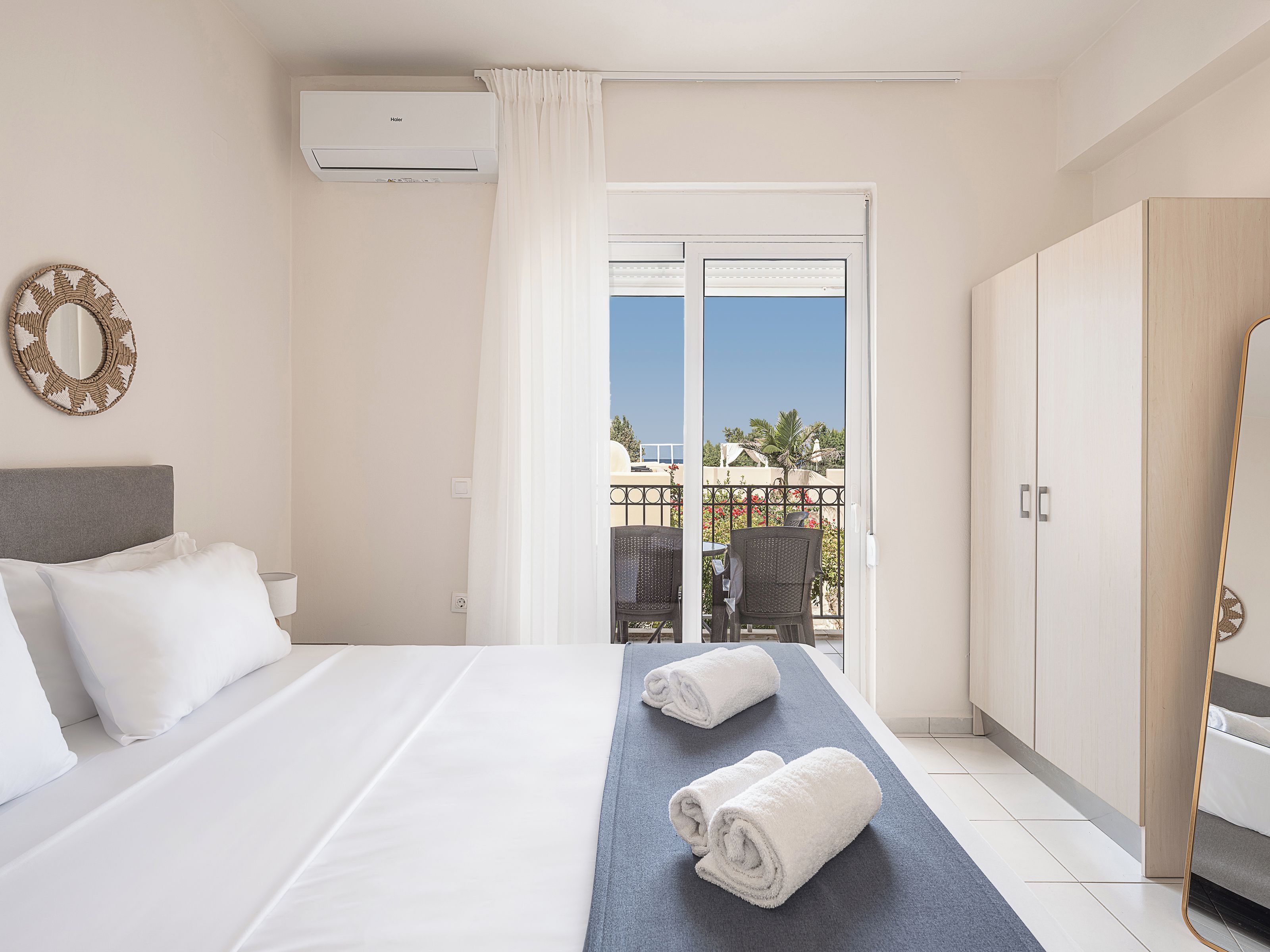 A hotel room with a bed, a balcony with a view, and a wardrobe.
