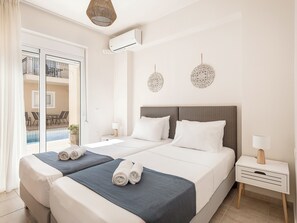 Une chambre d’hôtel avec un grand lit, deux tables de chevet, une fenêtre avec des rideaux et une vue sur une piscine et un espace de détente extérieur.