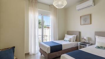 Quarto de hotel com duas camas, ventilador de teto, ar condicionado, um quadro emoldurado e vista para o exterior.