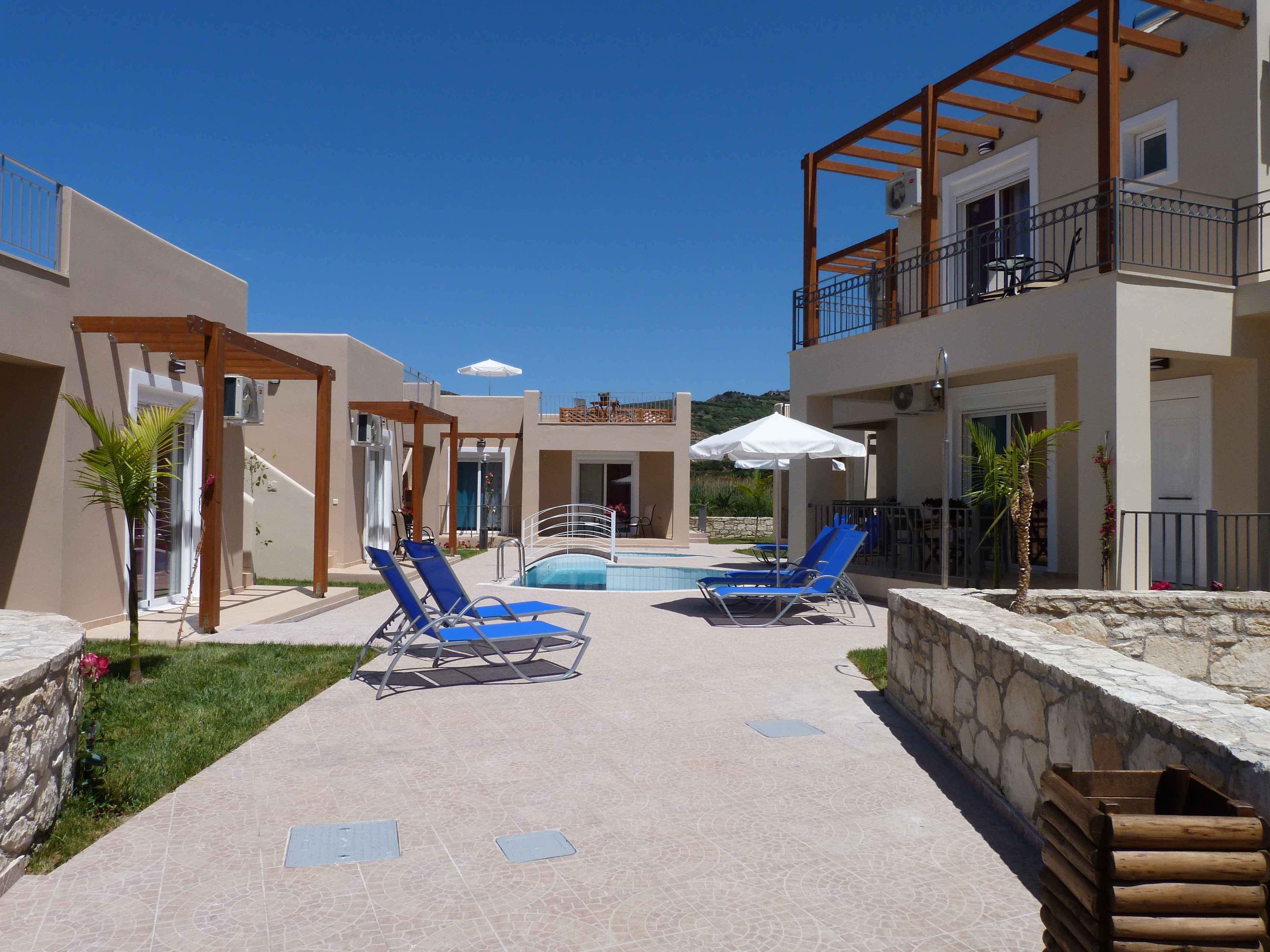 Un espace aménagé au bord de la piscine, avec des chaises longues, une piscine et un bâtiment doté de balcons.