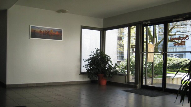 A spacious room with a large window, a potted plant, and a framed picture on the wall. - Canada Easy Lodge (Burnaby)