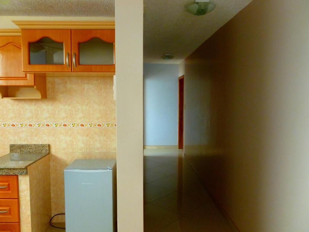 Una cocina con armarios de madera, un refrigerador y un salpicadero de azulejos.