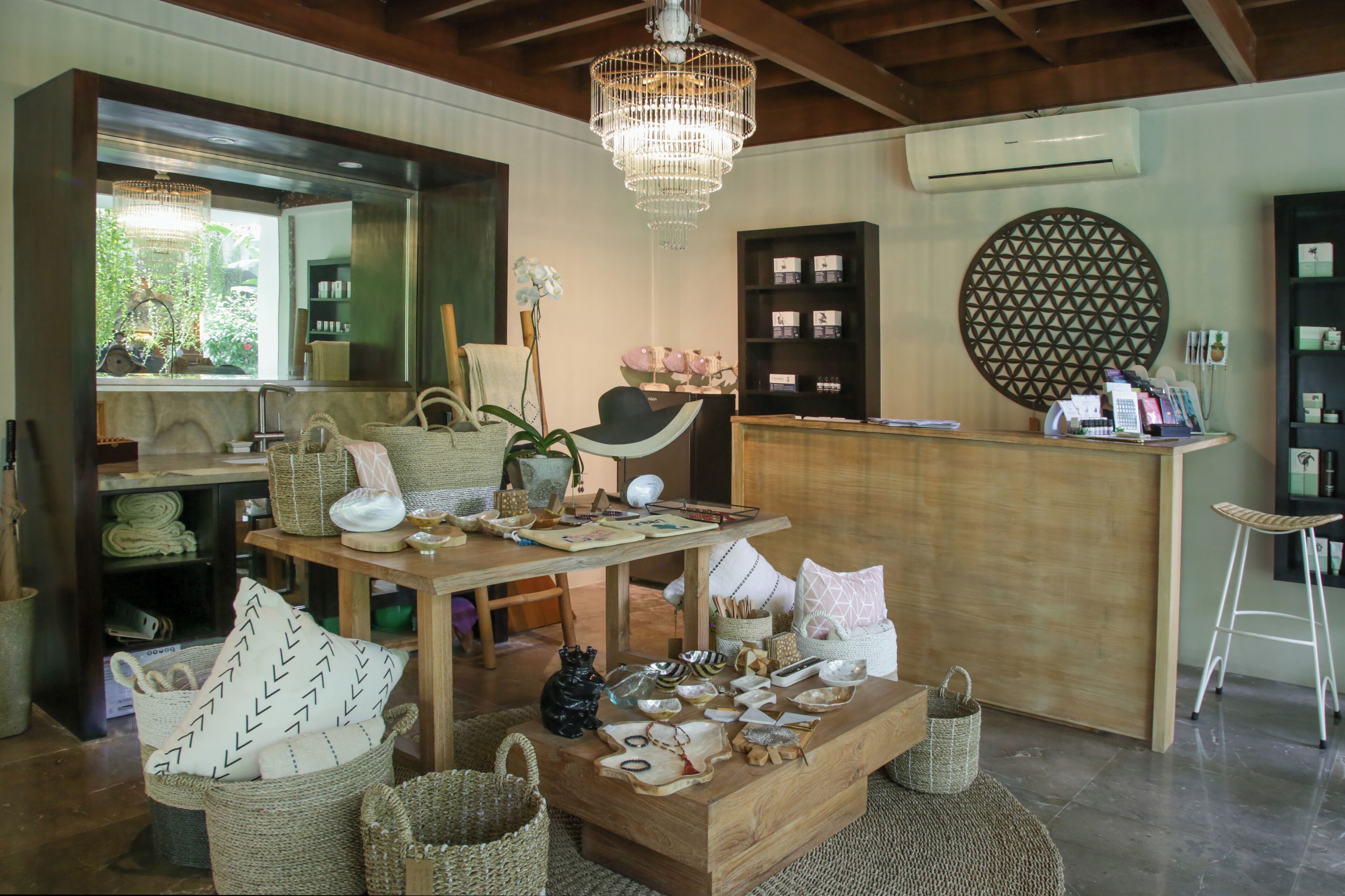 A cozy interior with a wooden reception desk, wicker baskets, and a chandelier.