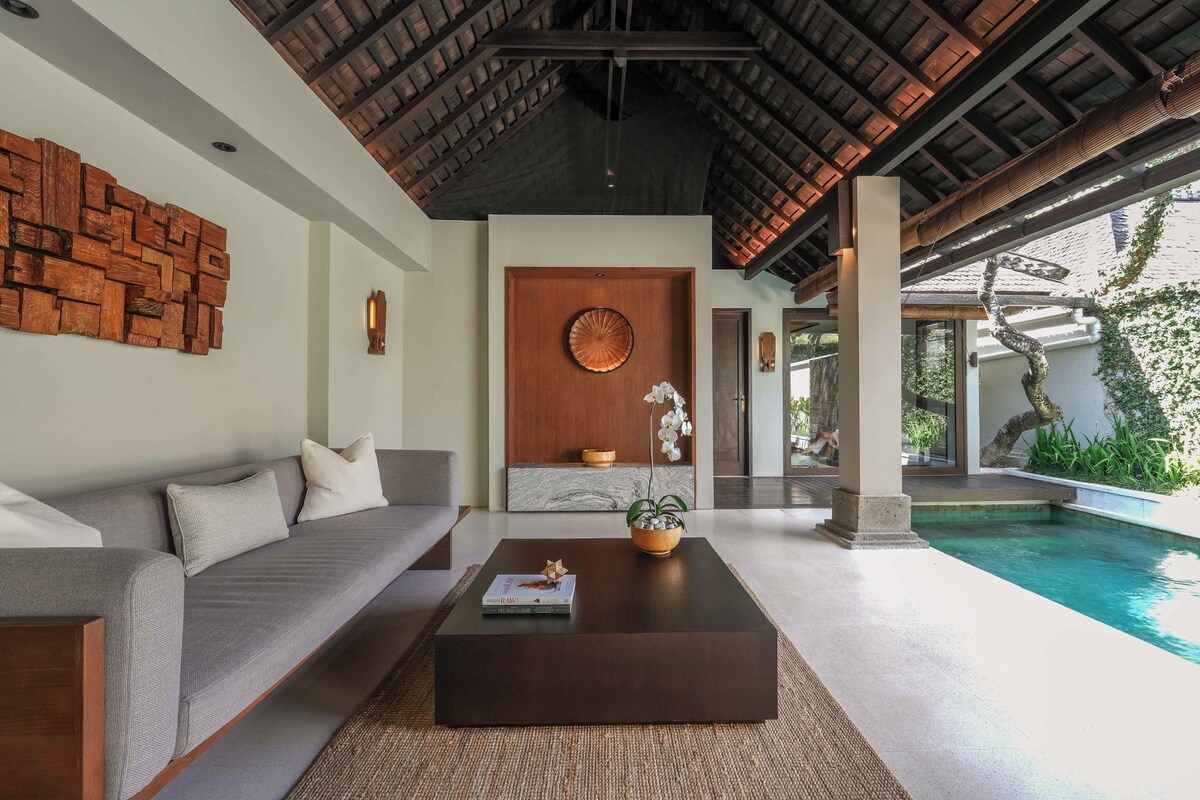 A modern interior with a pool, a wooden ceiling, and a sofa with cushions.