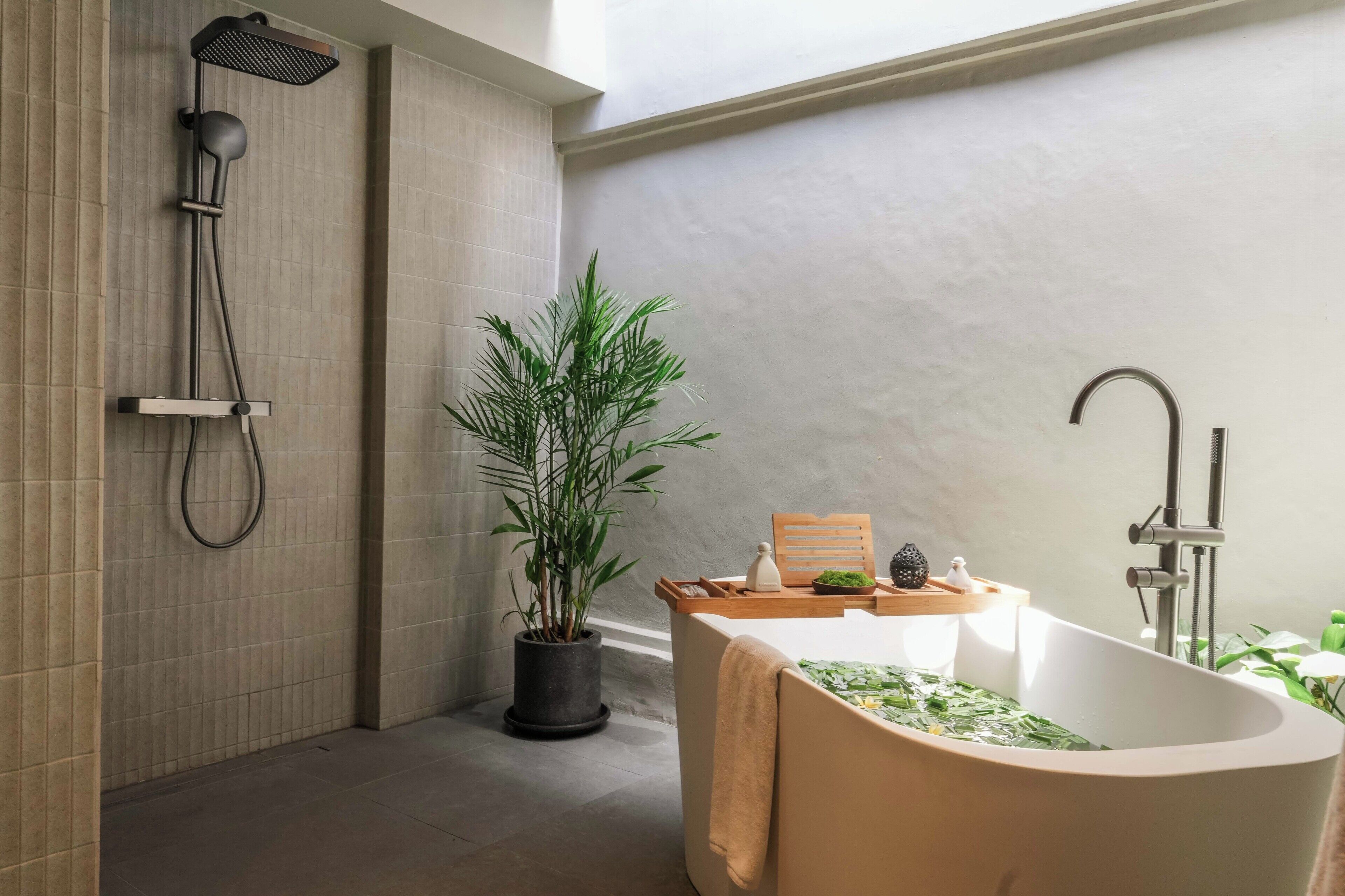 Un baño con una bañera independiente, un cabezal de ducha y una planta en maceta.