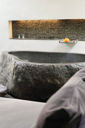 A modern bathroom with a stone sink, a built-in shelf with a flower, and a stone wall. - The Amala Boutique Retreat (Seminyak)