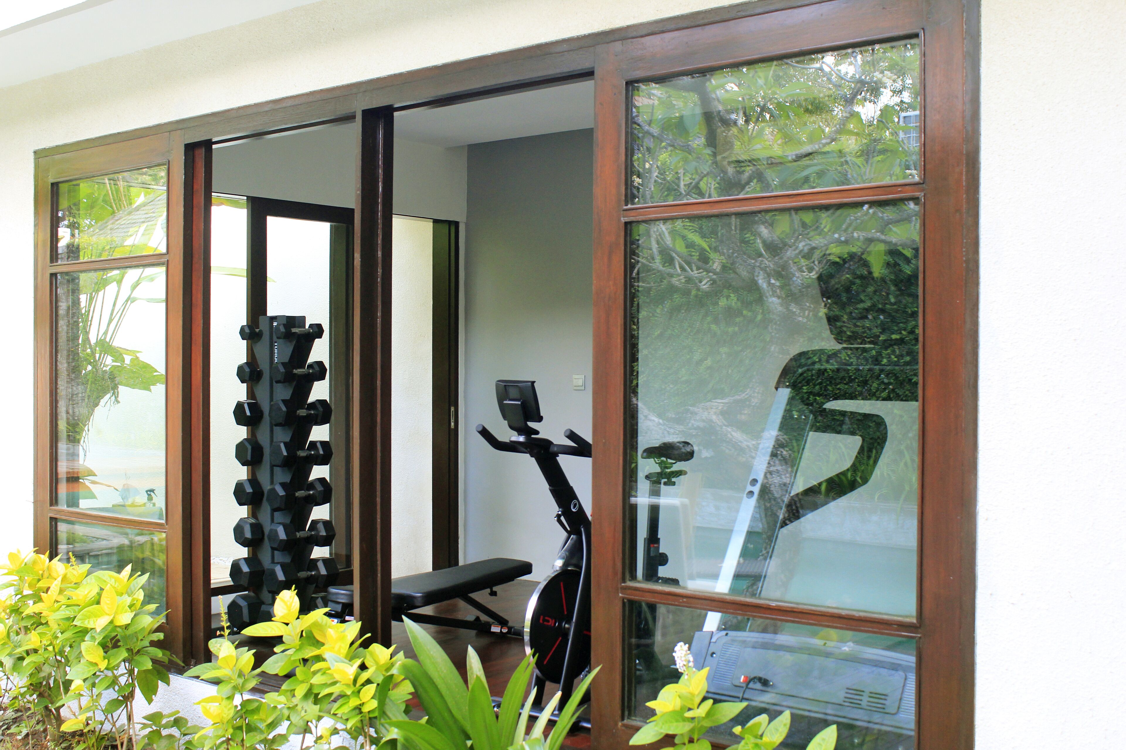 A home gym with exercise equipment, including a bench, dumbbells, and an exercise bike.