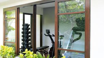 A home gym with exercise equipment, including a bench, dumbbells, and an exercise bike.