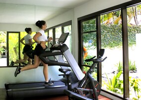 A gym with treadmills and exercise bikes, large windows with a view of greenery.