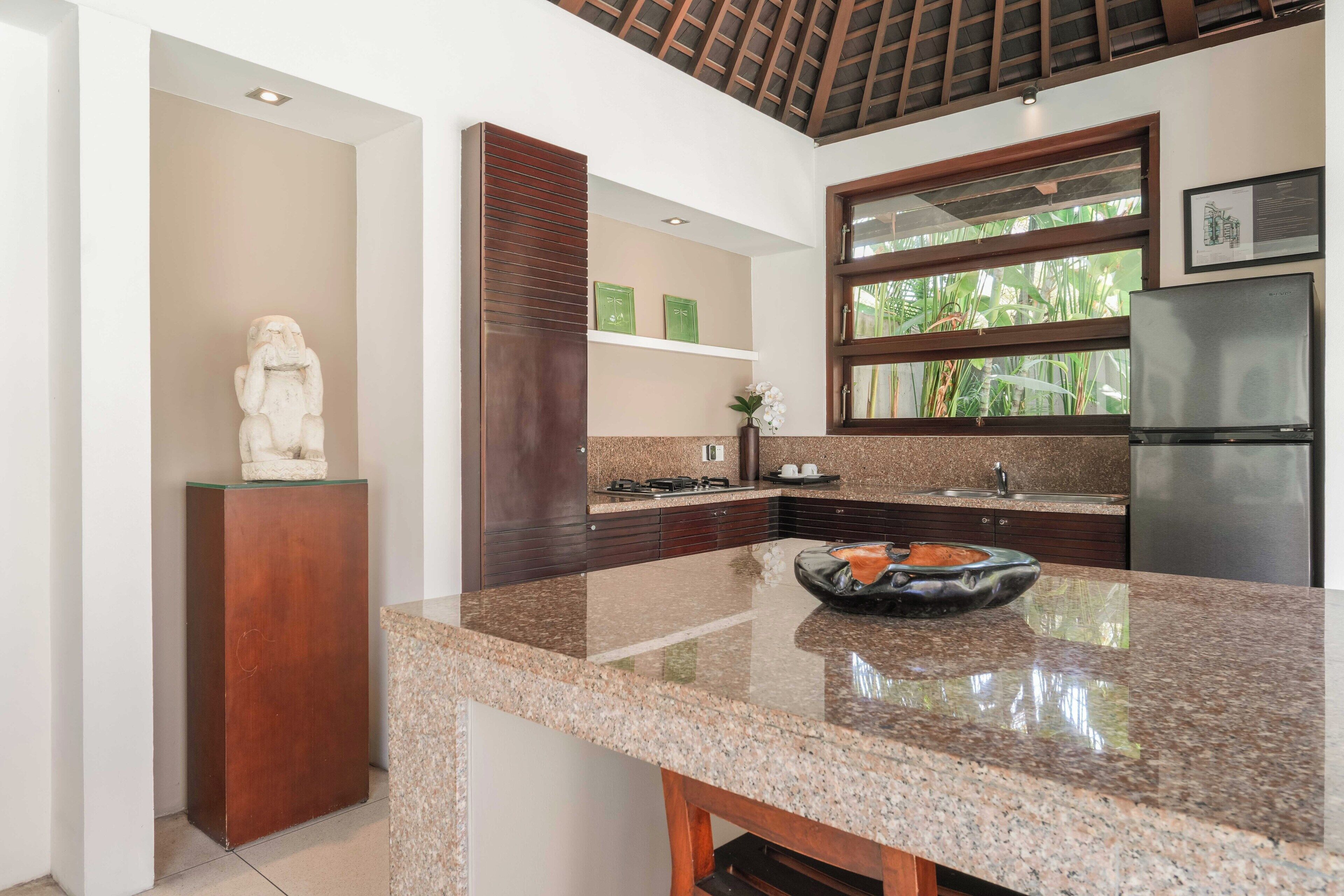 A kitchen with granite countertops, a stainless steel refrigerator, and a decorative bowl on the counter.