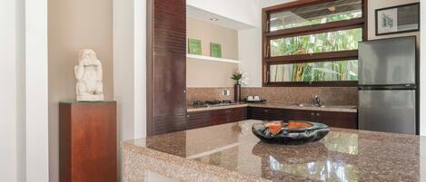 A kitchen with granite countertops, a stainless steel refrigerator, and a decorative bowl on the counter.