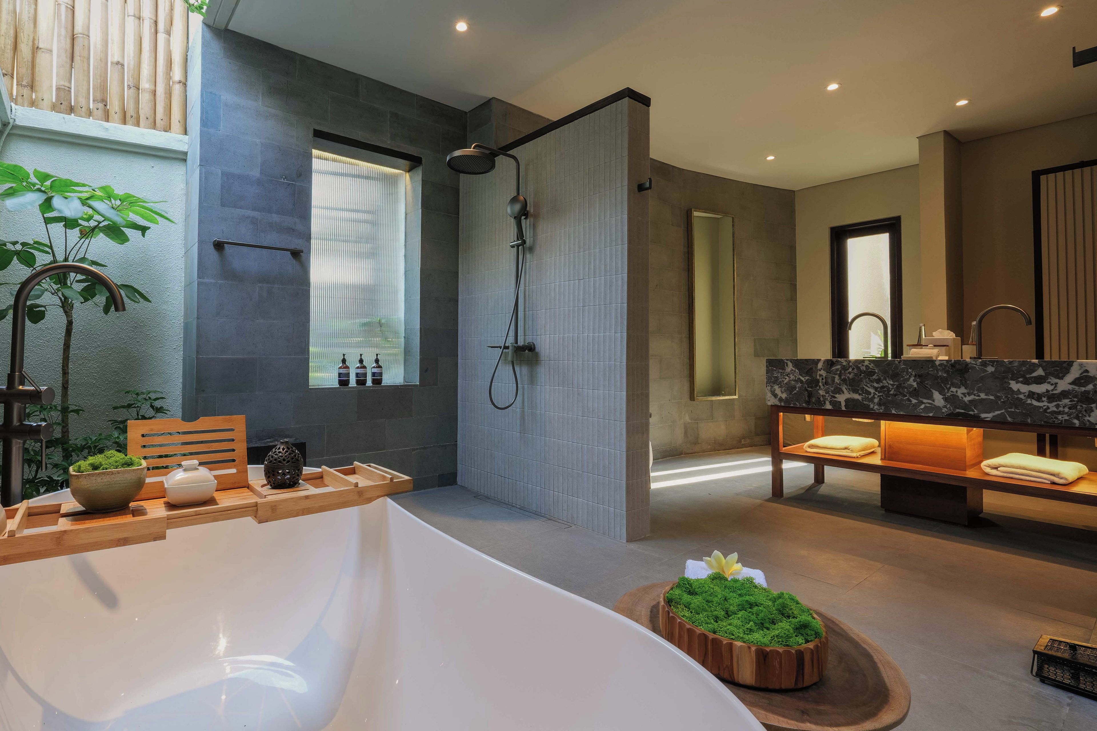 Ein modernes Badezimmer mit einer großen Badewanne, einer Dusche und einem Waschtisch mit Marmorplatte.