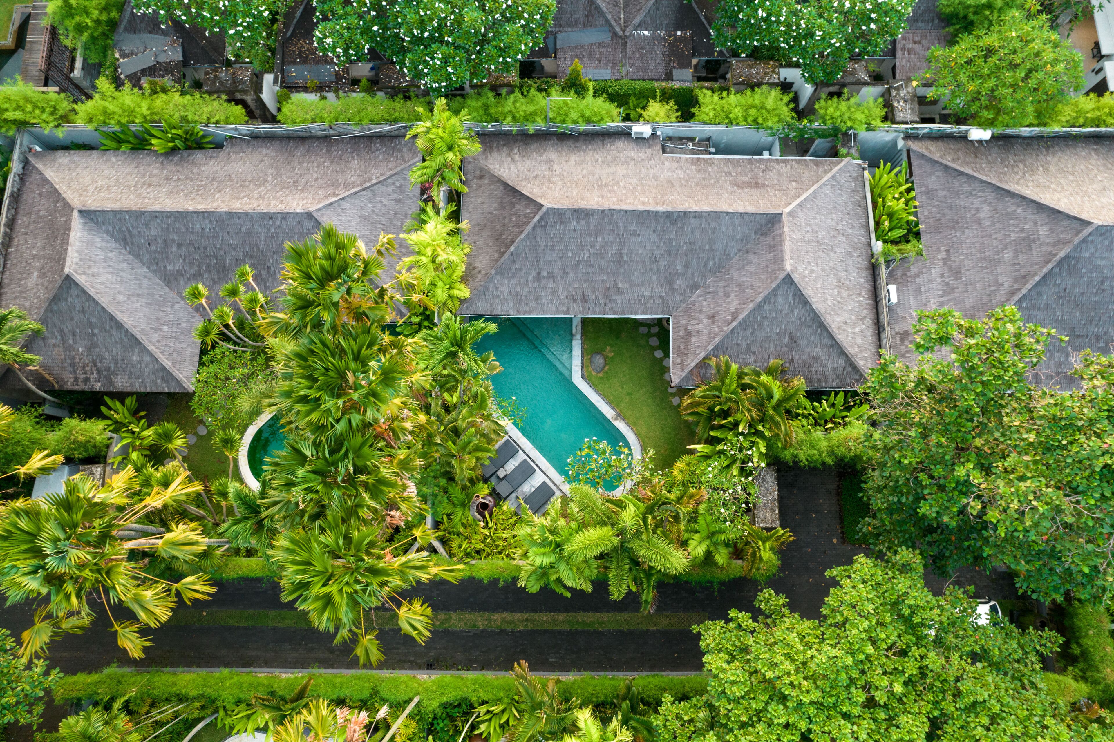 Un resort con varias edificaciones, piscina y abundante vegetación.