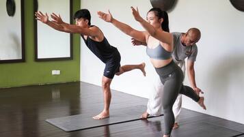 A group of people practicing yoga in a room with wooden flooring and a green wall.