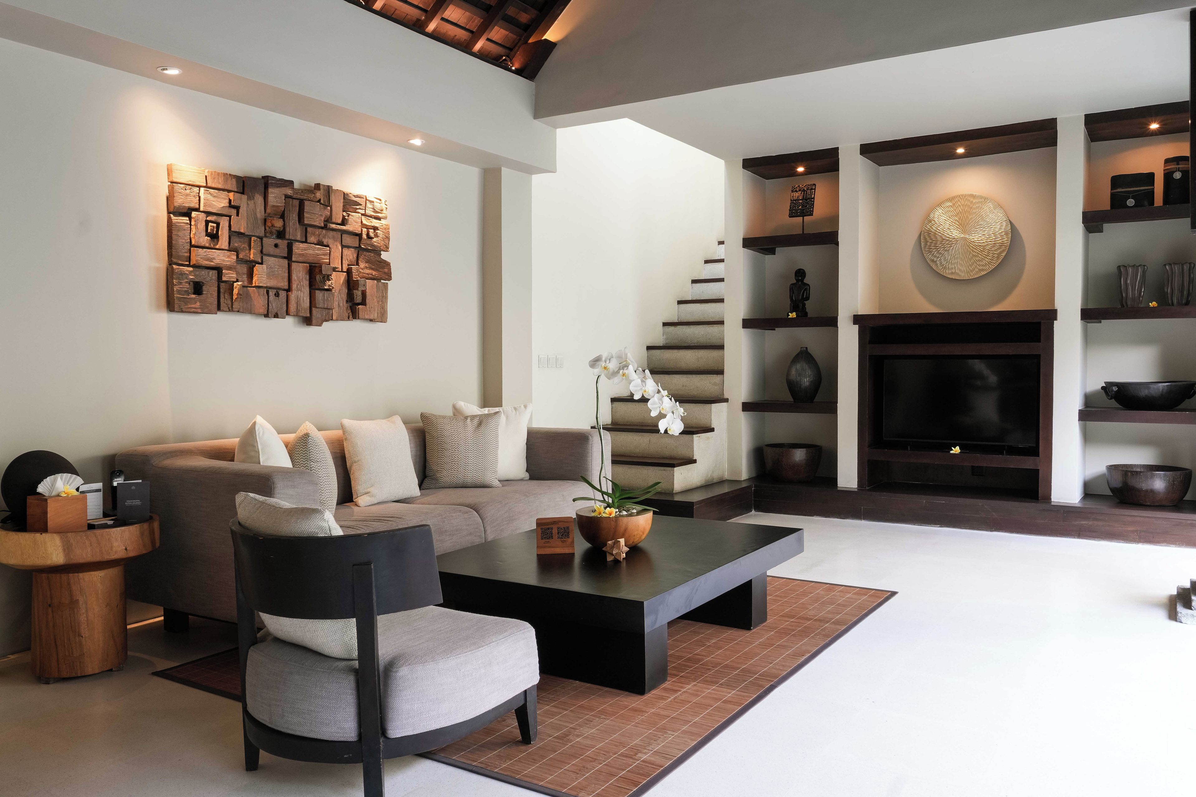 A modern living room with a sectional sofa, a coffee table, a fireplace, and a staircase.