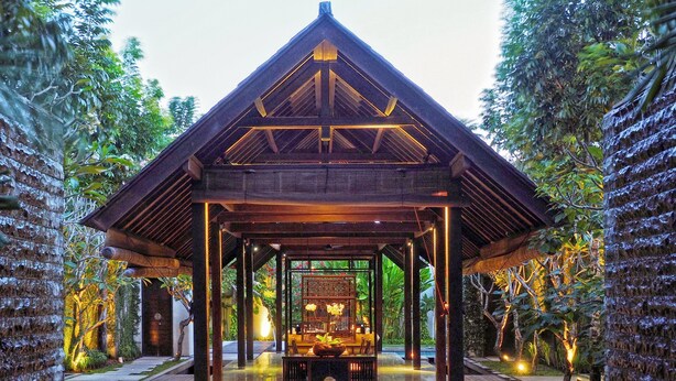 Un pavillon en bois doté d’un sol carrelé, entouré d’une végétation luxuriante.