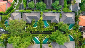 Vue aérienne d’un complexe hôtelier doté de plusieurs piscines, entouré d’une végétation luxuriante et présentant une architecture moderne.