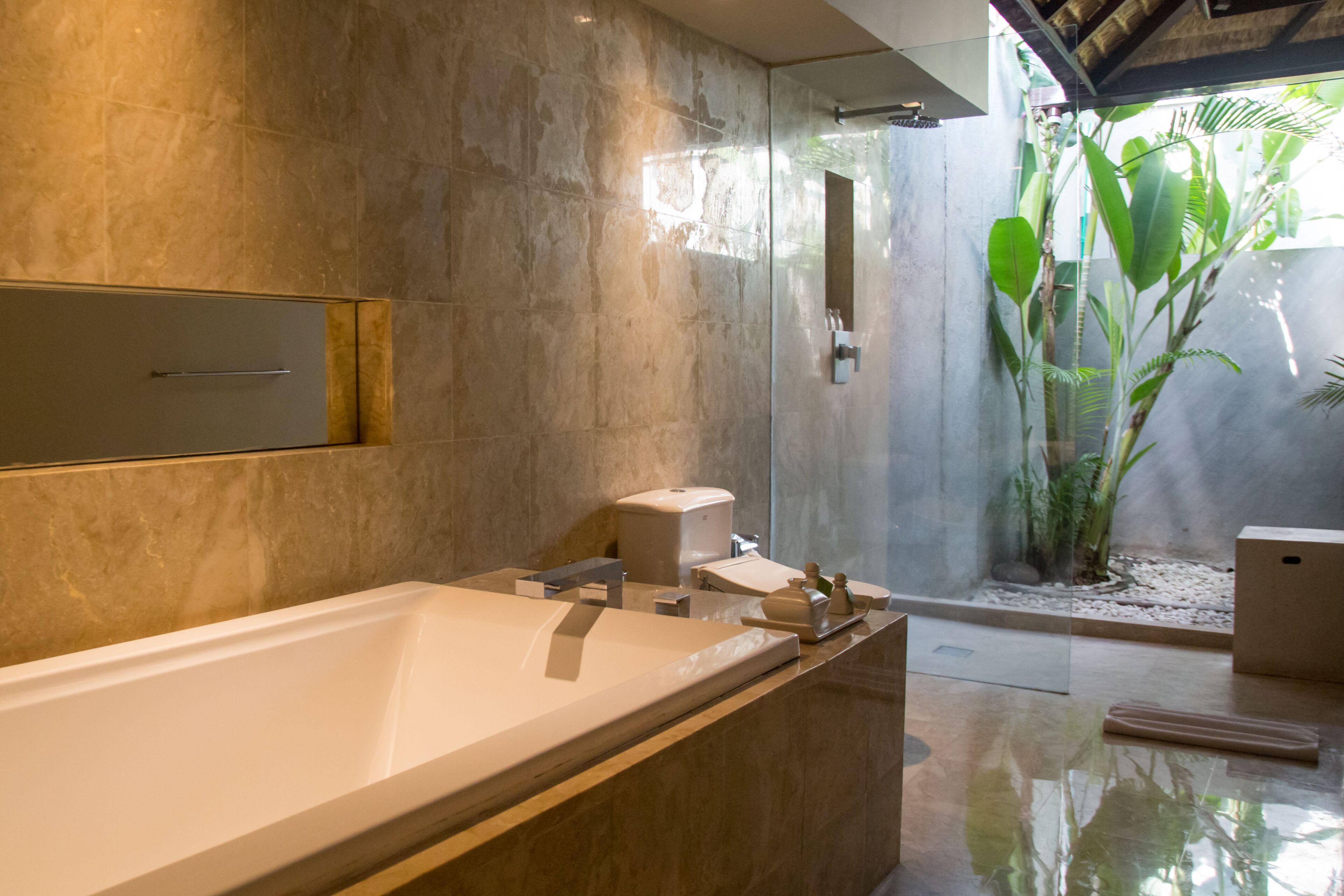 Ein modernes Badezimmer mit einer großen Badewanne, einer Duschkabine aus Glas und einem kleinen Innenhof.