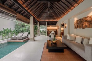 Een modern interieur met een zwembad, lounge stoelen en een eethoek.