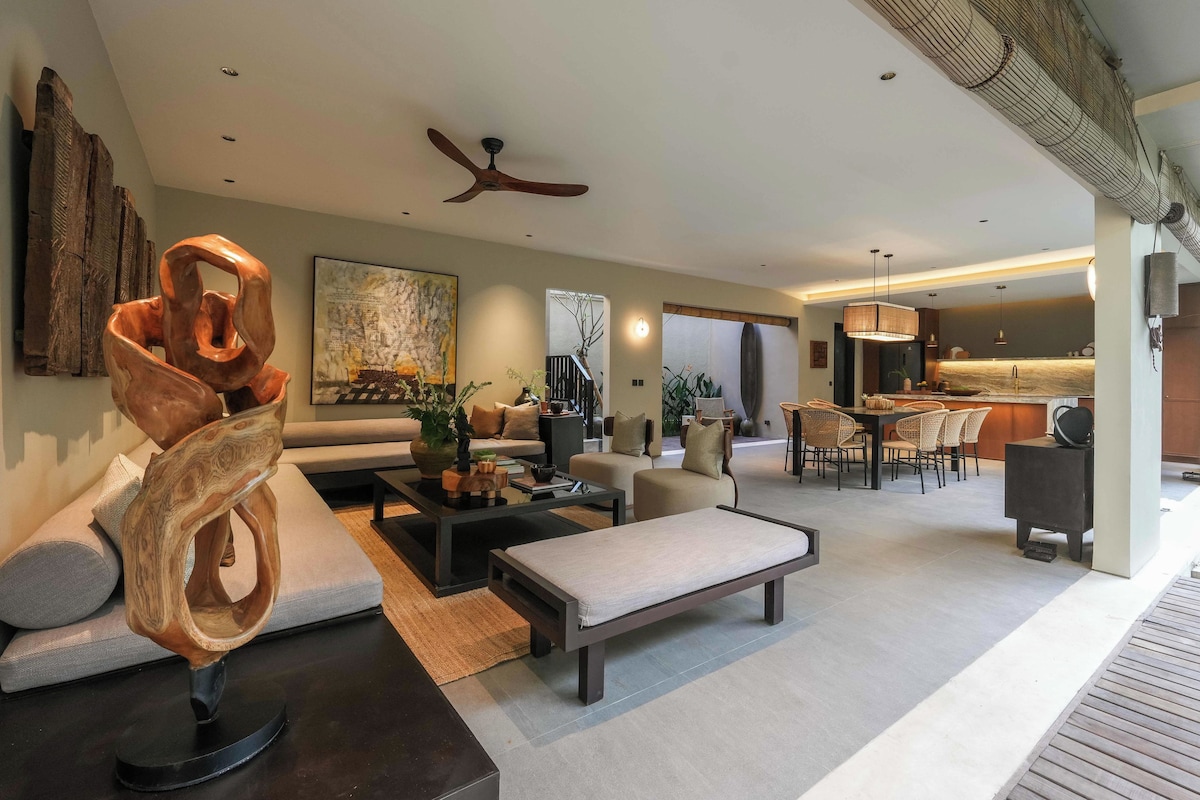 A modern living room with a sofa, coffee table, and a unique wooden sculpture.