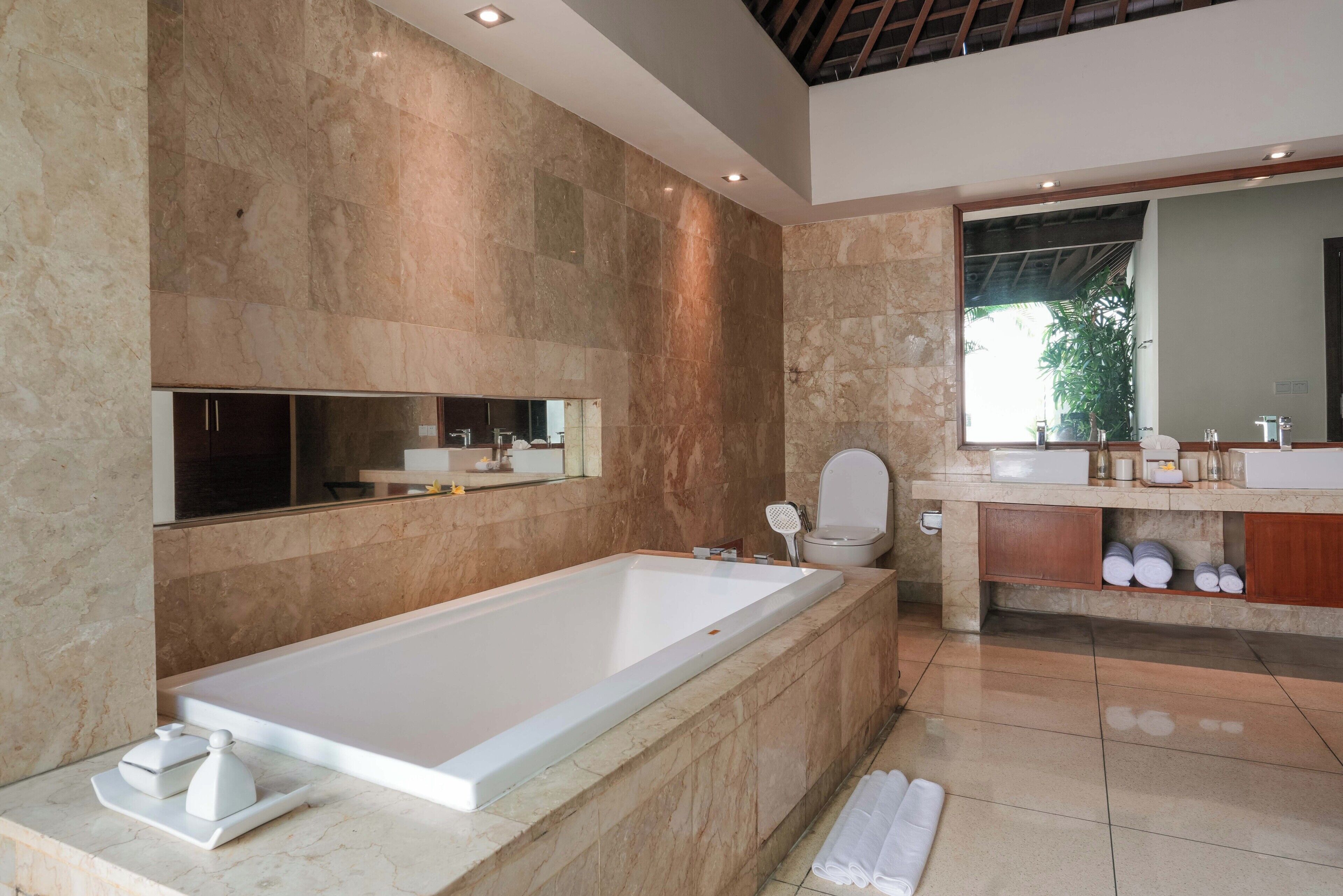 A modern bathroom with a large bathtub, a toilet, and a vanity with a mirror.