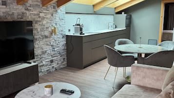 Un loft moderno con una pared de piedra, un televisor de pantalla plana, una mesa de centro de mármol, un sofá y una cocina con encimera y armarios.