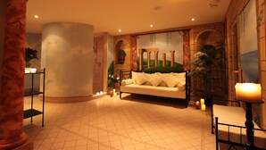 A spacious lobby with a large column, a sofa, and a small table with candles.