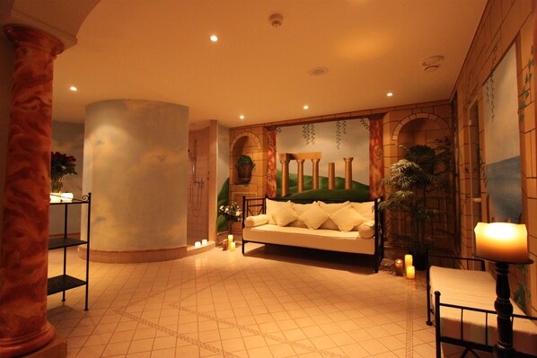 A spacious lobby with a large column, a sofa, and a small table with candles. - Hotel Albatros Zermatt (Zermatt)
