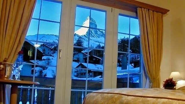 A hotel room with a large window offering a view of a mountain and a cabin.