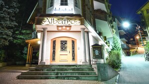 A hotel with a tower-like structure, a sign reading "Albatros Hotel," and a paved entrance area.