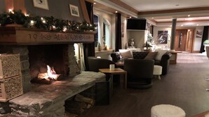 A cozy lounge area with a stone fireplace, comfortable seating, and a Christmas tree.