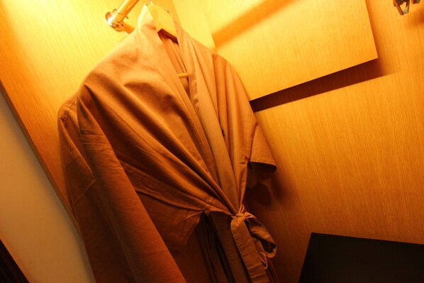 A room with a wooden wall and a hanging garment. - Ossotel Legian Bali (Legian)