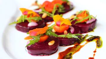 Ein Teller Essen mit Rote Bete Scheiben, Grünzeug und orangefarbenen Blüten.