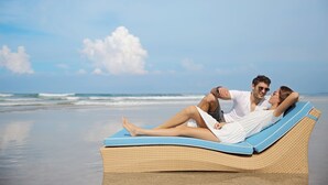 A couple relaxing on a wicker lounge chair with a view of the ocean. - Ossotel Legian Bali (Legian)