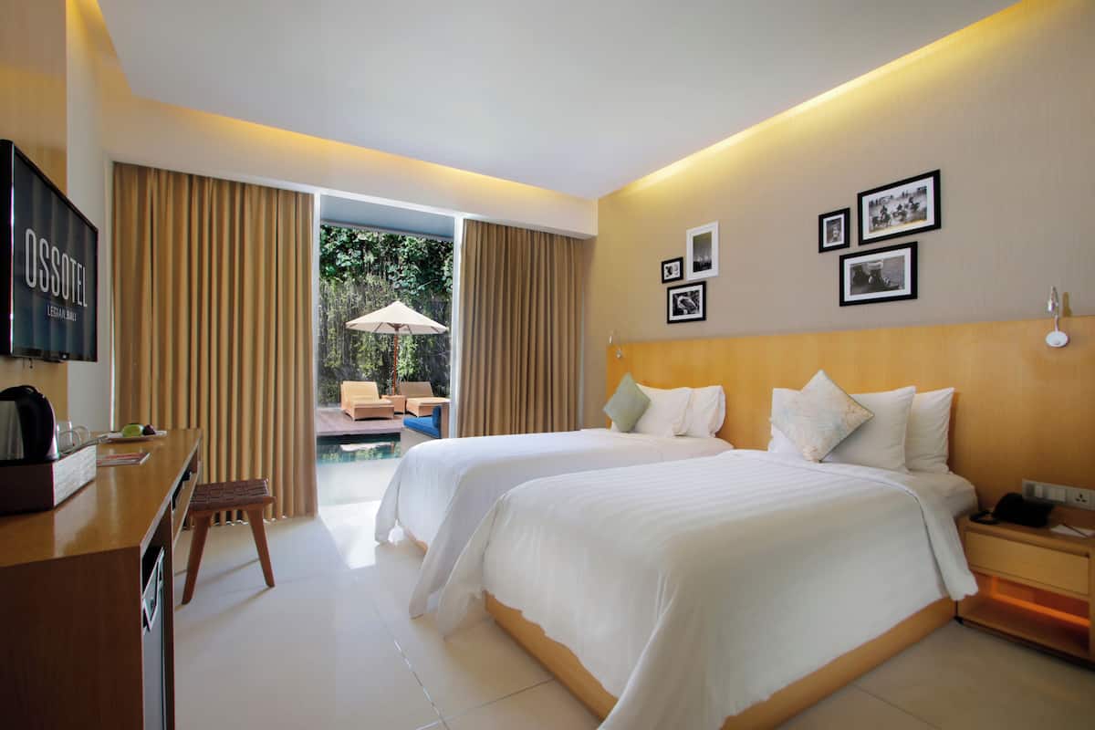 Habitación de hotel con dos camas, un escritorio, un televisor y vistas al exterior.