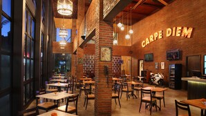 A restaurant interior with brick walls, wooden tables, and hanging lights. - Ossotel Legian Bali (Legian)