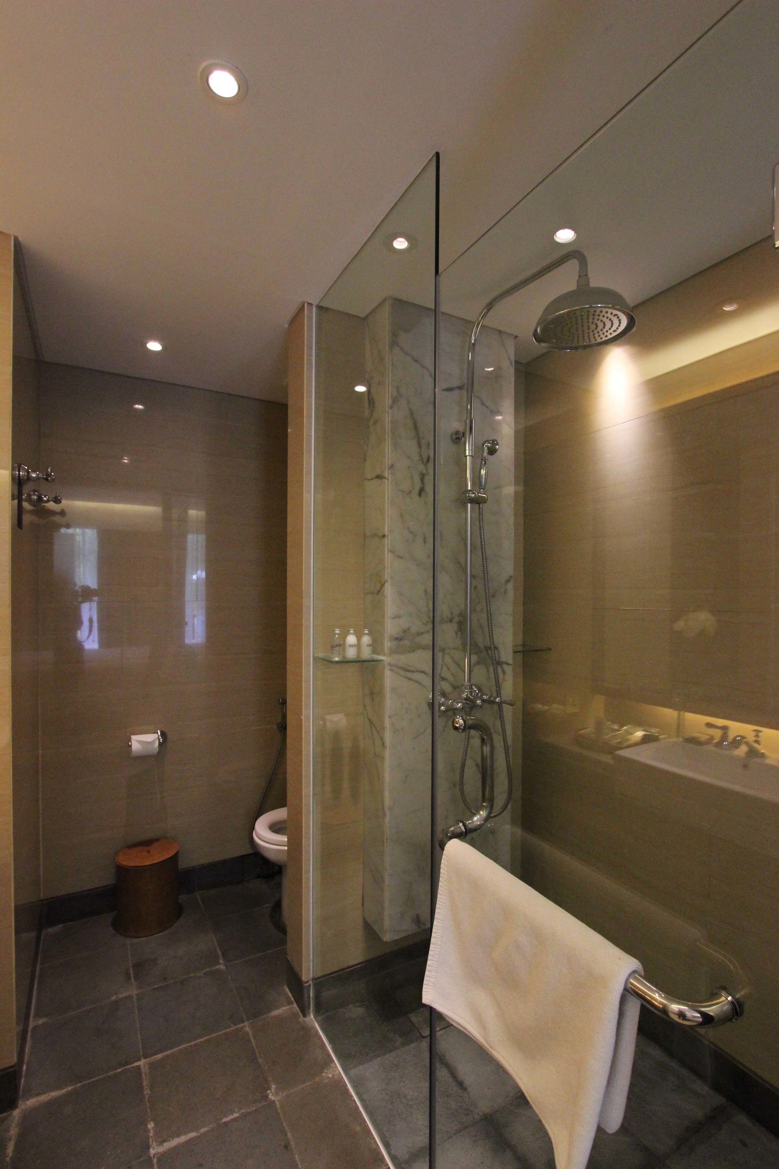 A modern bathroom with a glass-enclosed shower, a visible toilet, and a glass-topped sink.