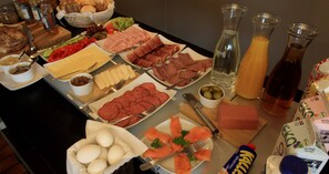 Un buffet proposant une variété de plats, notamment des viandes, des fromages et des œufs.